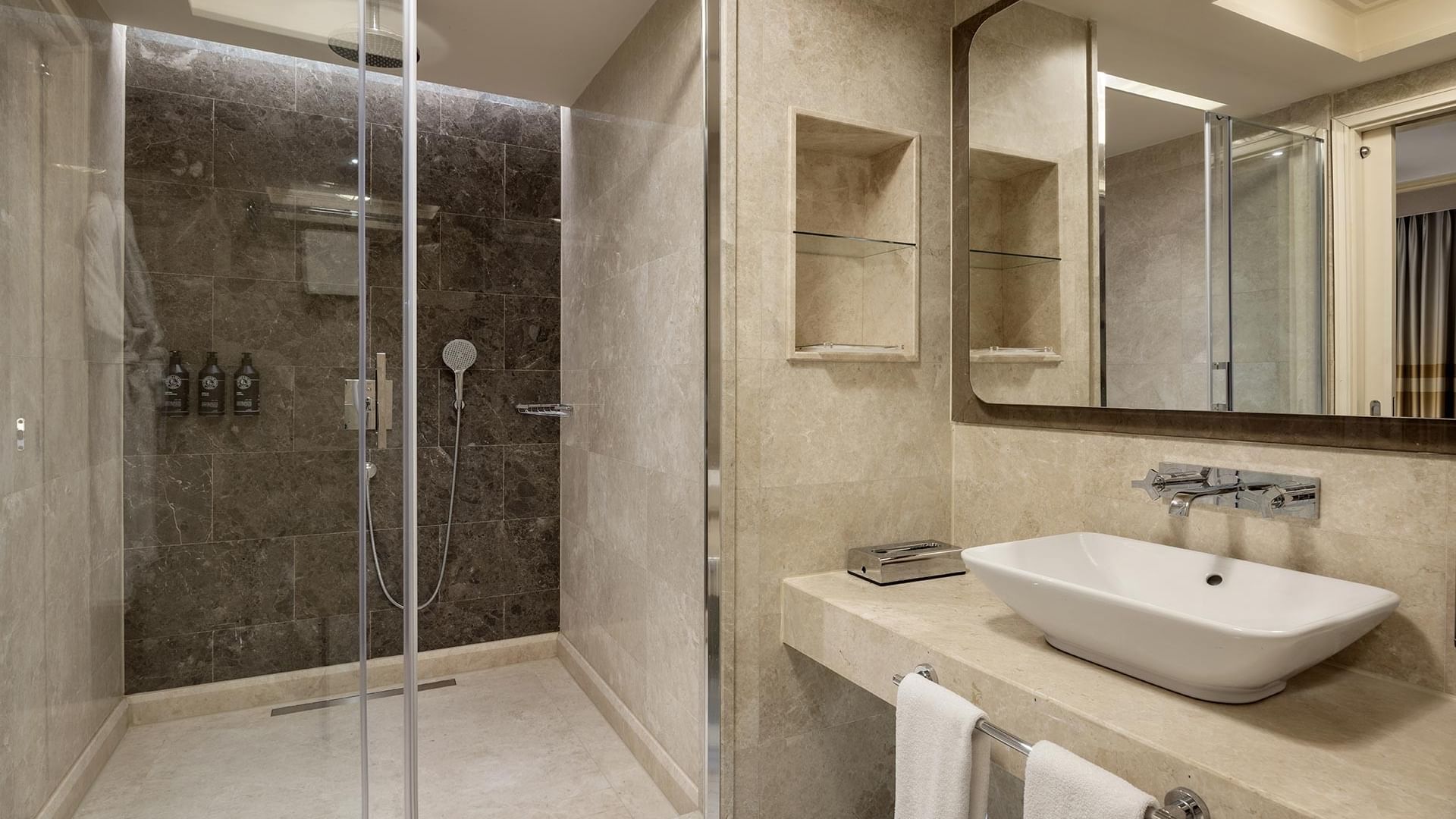 Modern suite bathroom with shower, sink, mirror, and two towels hanging on a metal rack at Titanic City Taksim.