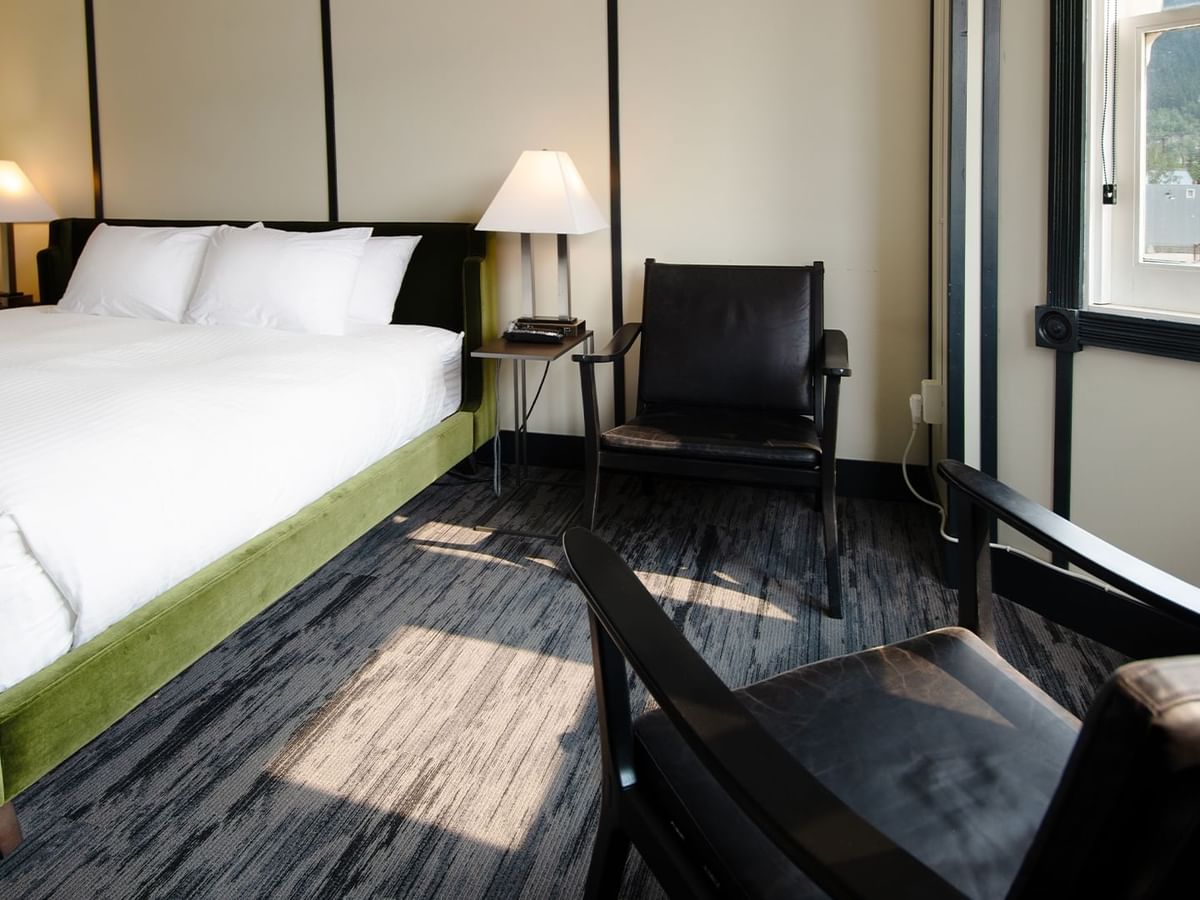 Hotel room with king bed, lamp, night stand, chair, and window