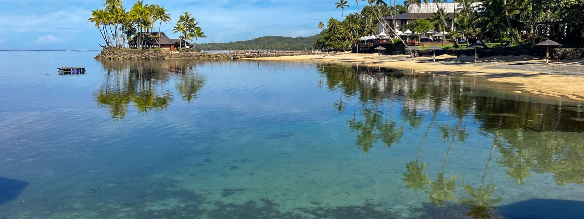 Clear water meets sandy beach lined with palm trees at Warwick Fiji Resort and Spa in Korolevu