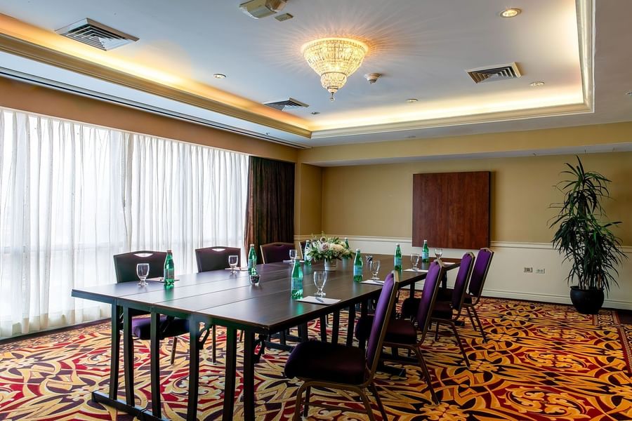 Cambridge at Warwick Denver with water bottles on a long table by purple chairs under a chandelier
