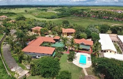 Aerial view of a stunning resort at La Casita by the Hub, featuring a vibrant pool, lush gardens, and a premier golf course