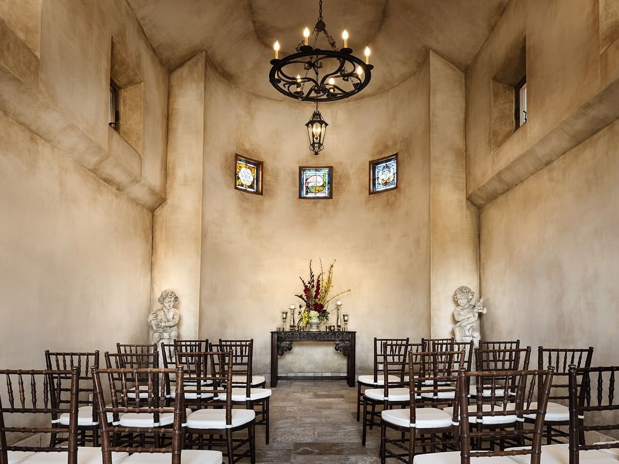 Inside the stucco Abbayy, four rows of chairs set for a small indoor wedding.