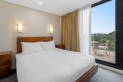 Nightstands by the cozy bed in Three Bedroom Riverview Penthouse with a balcony lounge at Amora Herencia Riverwalk Melbourne