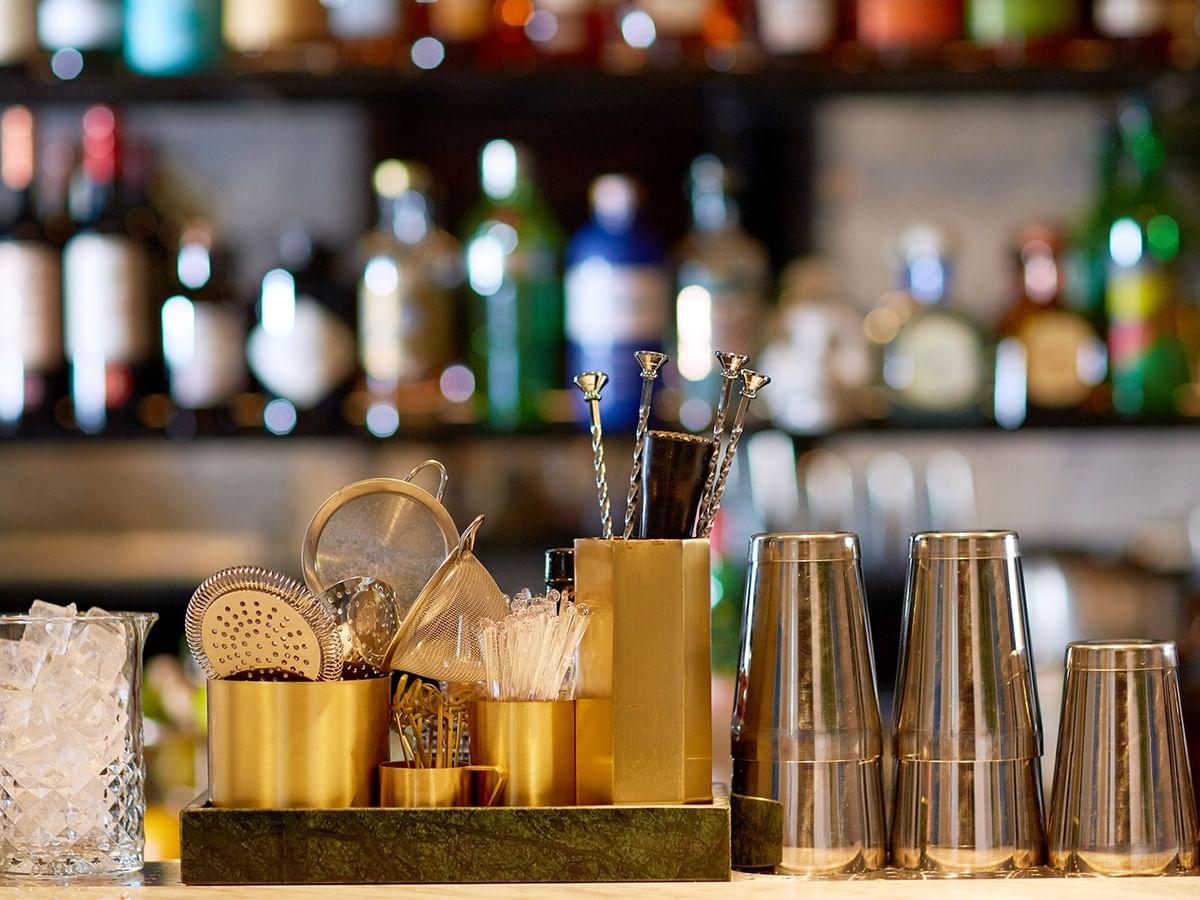 Bar setup with cocktail tools, ice-filled glasses, and shakers at Glacier Bar & Lounge, Coast Langley City Hotel.