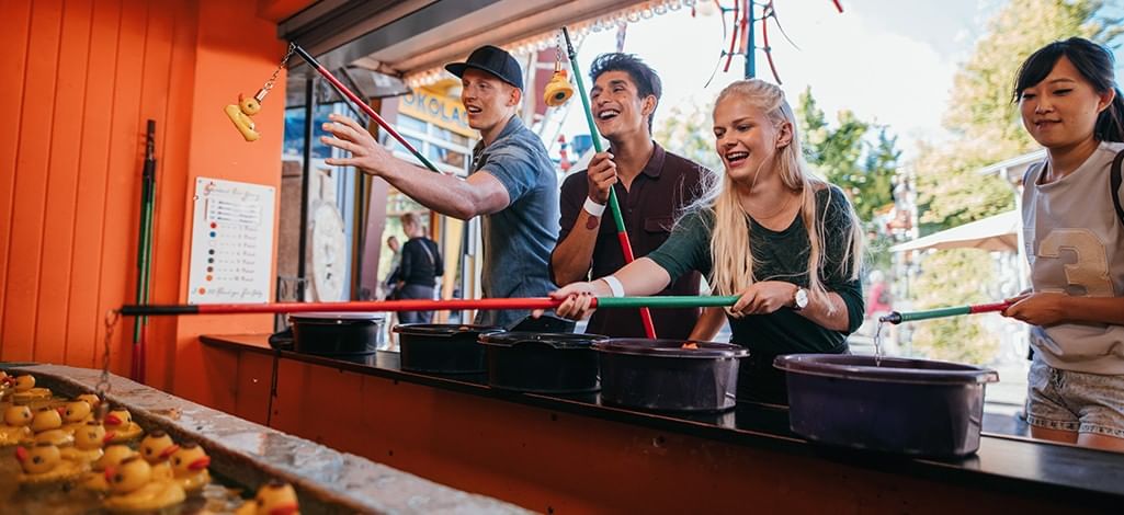 Friends playing a rubber duck fishing game at a midway booth