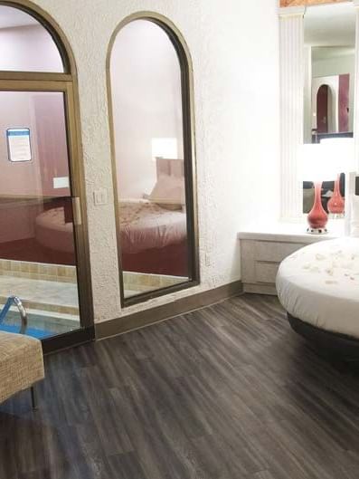 Interior of Garden of Eden Apple with a bed arranged with flower petals & a pool view at Cove Pocono Resorts