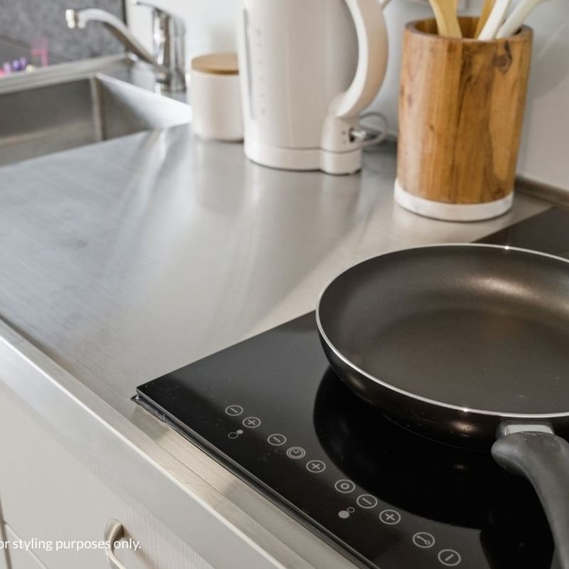 Frying pan on an induction stove with kitchen utensils nearby at Mayoral Drive Student Accommodation.