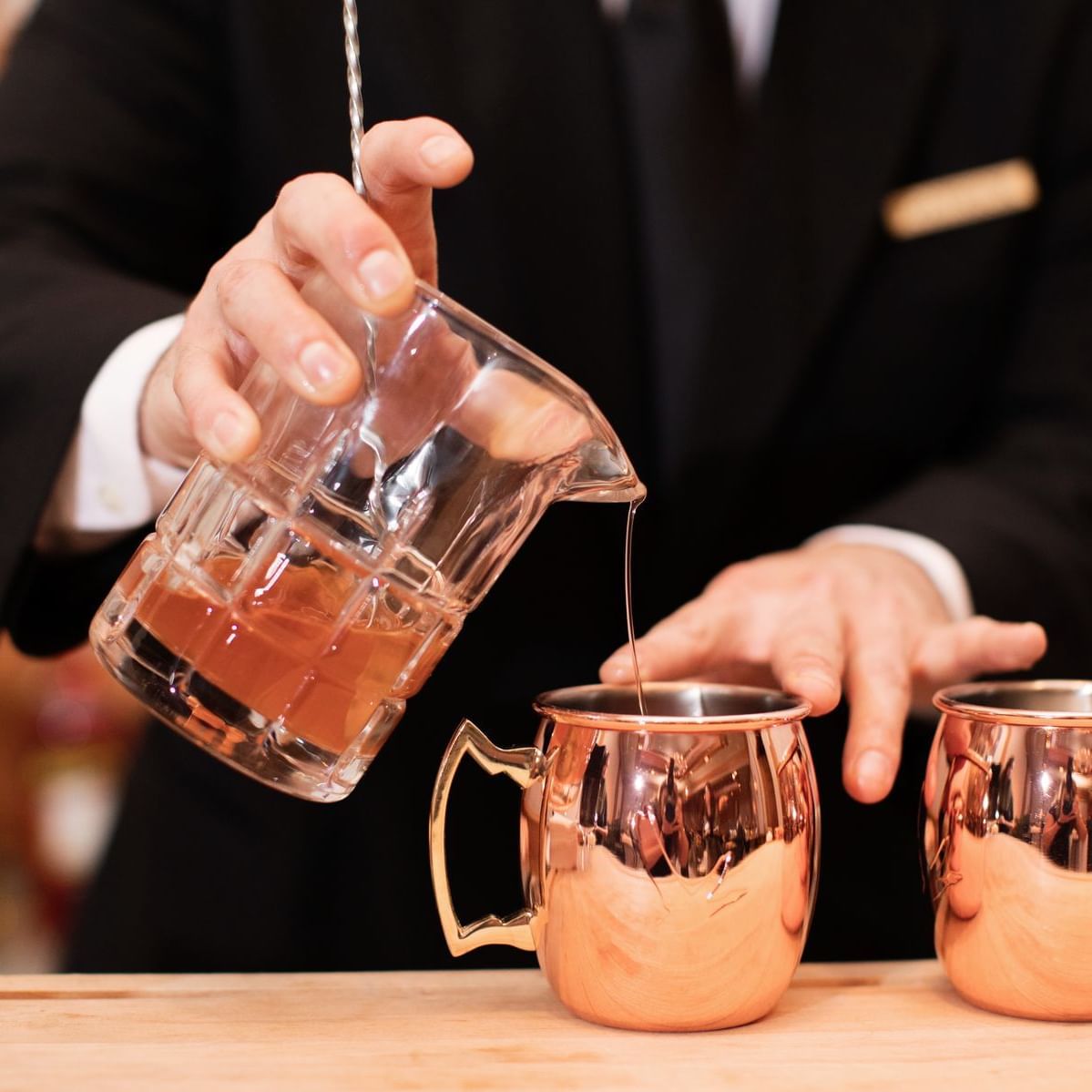 Close-up of bartender pouring a cocktail on The Bar & Lounge counter at The Umstead Hotel and Spa