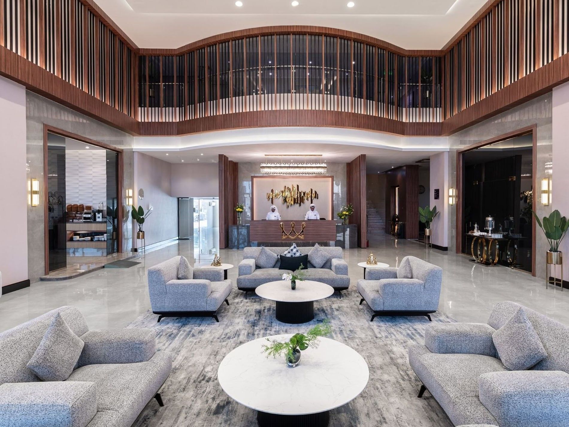 Grey plush chairs and round marble tables surrounding a large rug in a lobby at Warwick Al Jubail