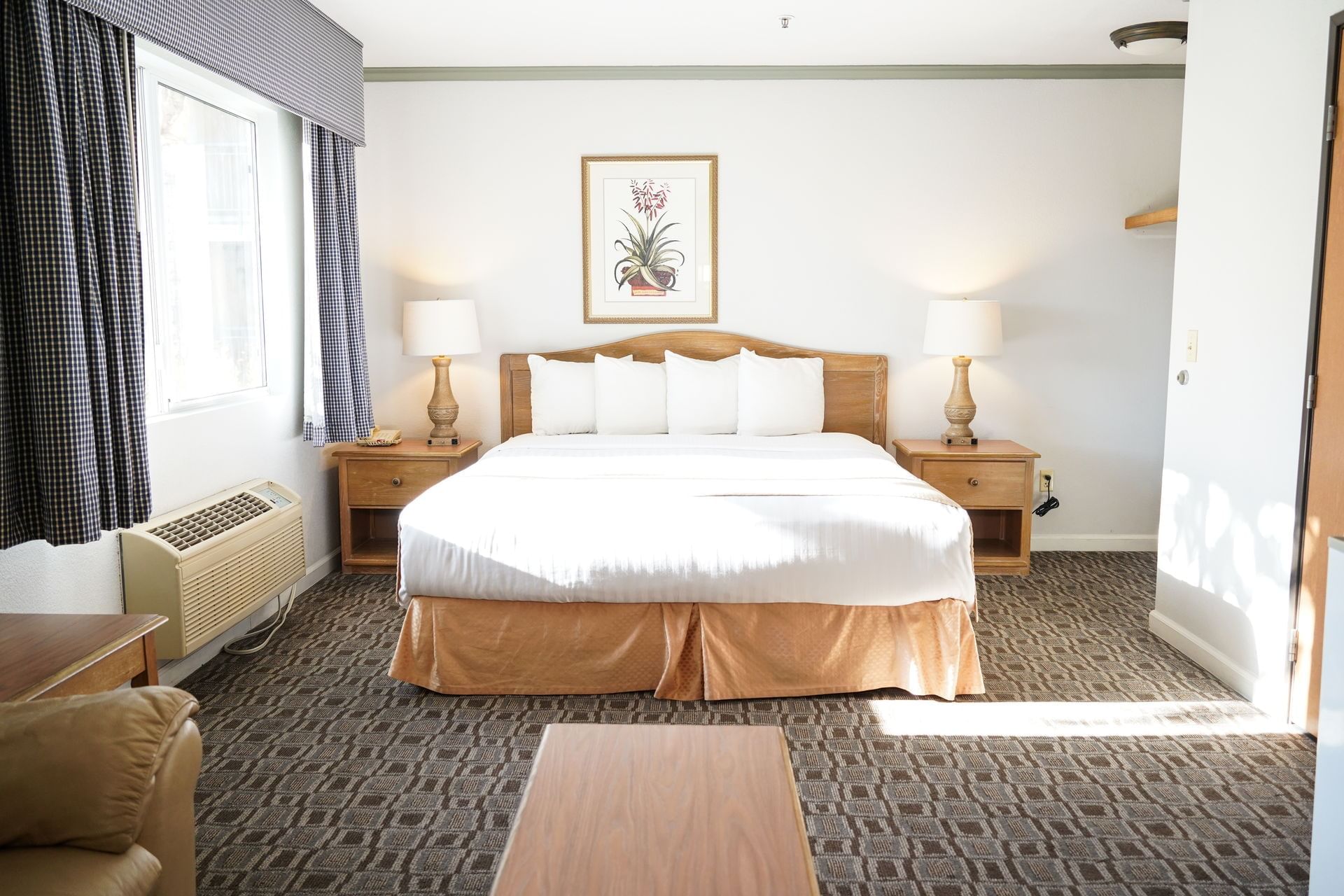 A wide view of a hotel room with a large bed, two nightstands, and a window.