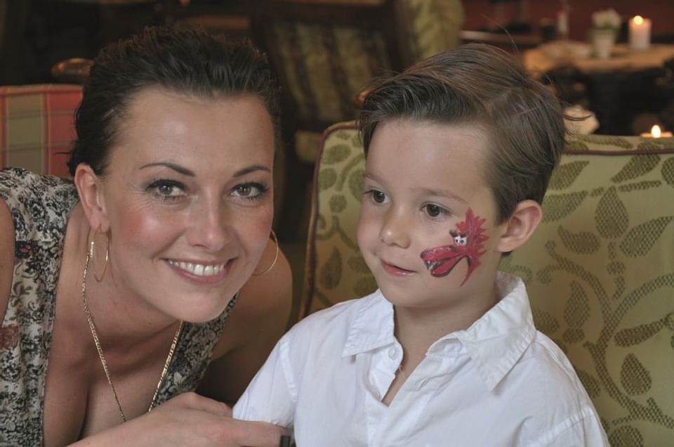 A kid with a face painting posing with his mom at Liebes Rot