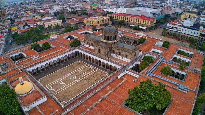 Aerial view of a stone courtyard by an old dome, surrounding the city at Camino Real Pedregal Mexico