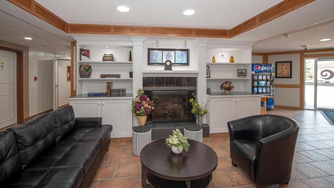 Hotel lobby lounge with black sofas, coffee table and front desk at Coast Whitecourt Hotel