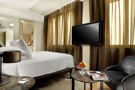 Comfy bed, TV and sitting area in Deluxe room at Rome Luxury Suites