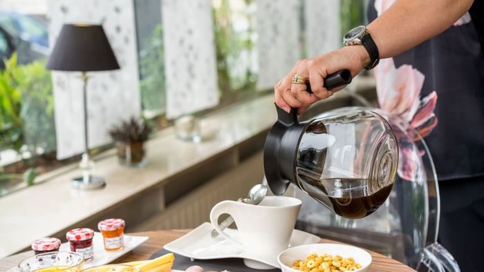 A waiter pouring coffee into a cup at Hotel Napoleon