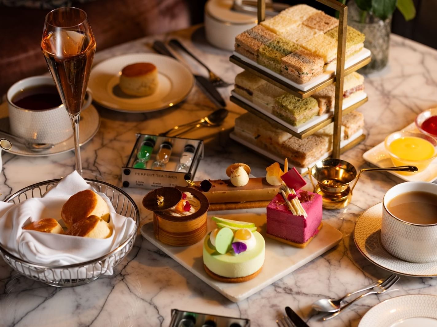 Variety of food, sweets & beverages served on a marble table at The Londoner Hotel