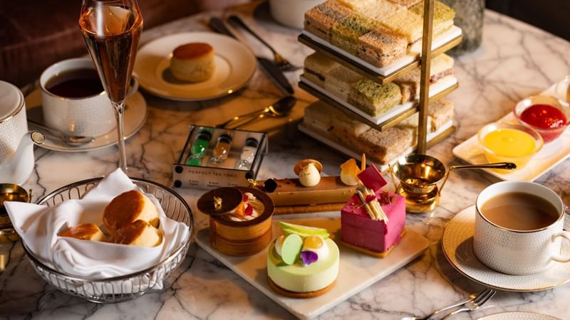 Variety of food, sweets & beverages served on a marble table at The Londoner Hotel