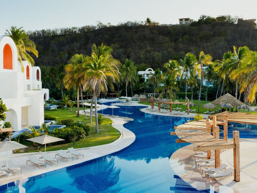 Camino Real Zaashila Huatulco tropical de lujo con piscina serpenteante rodeada de palmeras y villas blancas