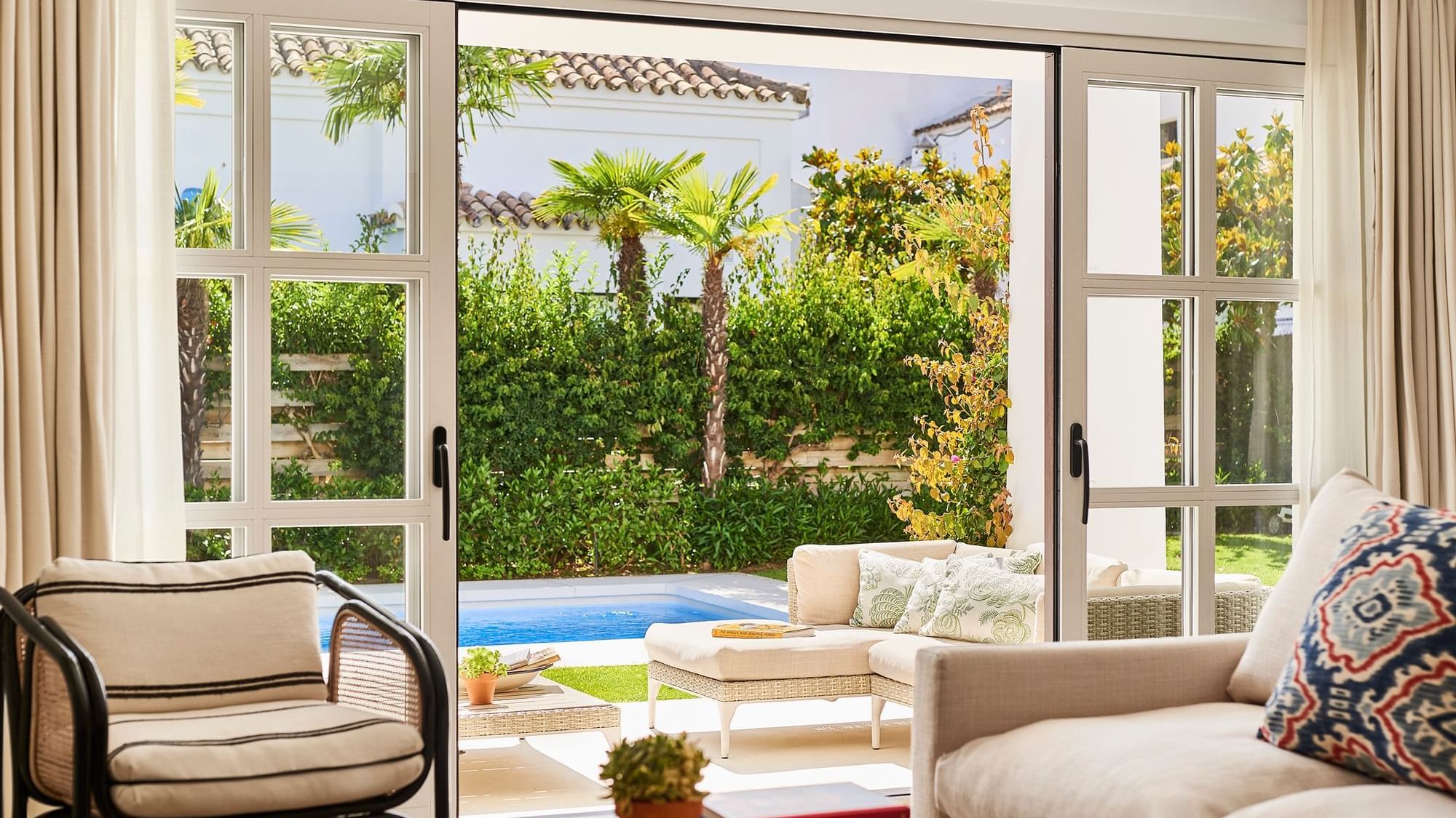 Living area with a sofa and pillows on a patterned rug in a 3-bedroom villa with a kitchen at the Marbella Club
