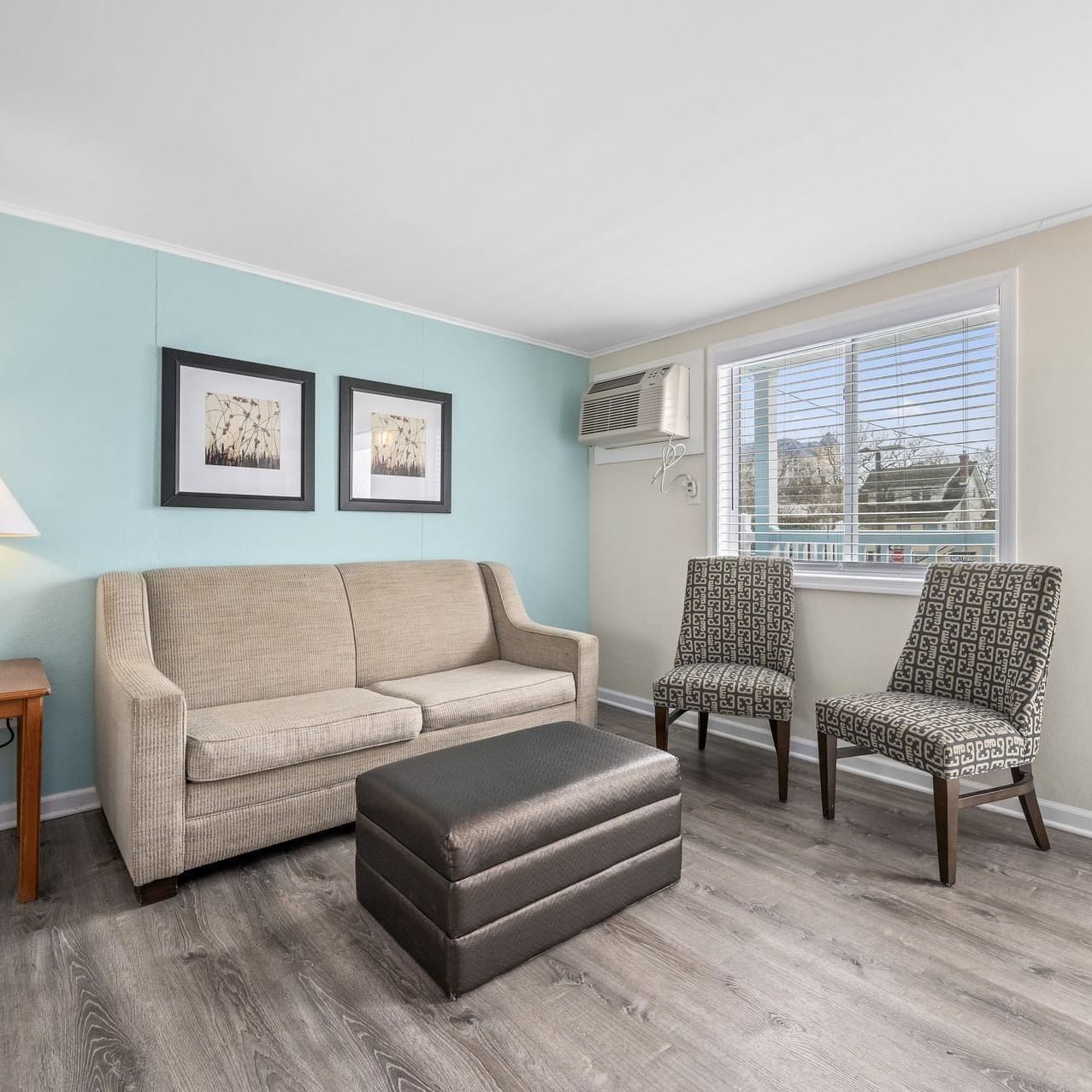 Deluxe Queen Suite living area with a sofa, patterned chairs, a lamp, and a window at Madison Beach Motel