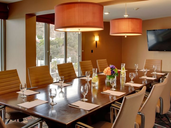 A conference room with a long table, chairs, and lighting fixtures.