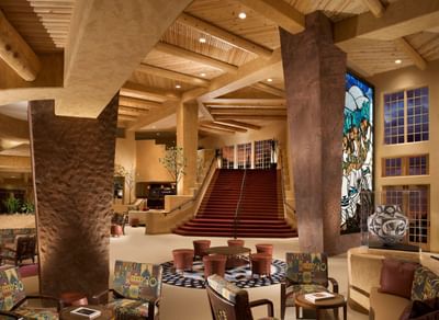 Grand lobby at Hilton Santa Fe Buffalo Thunder featuring a red carpet staircase and a colorful glass window