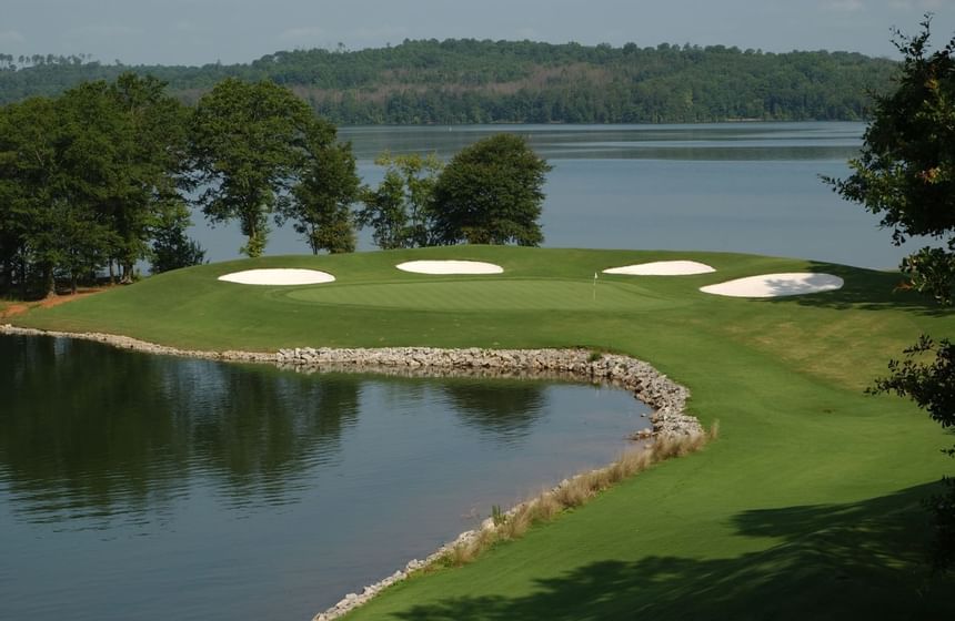 Lakeside golf green edged by four white sand bunkers and lush forest trees at Clemson University Conference Center & Inn