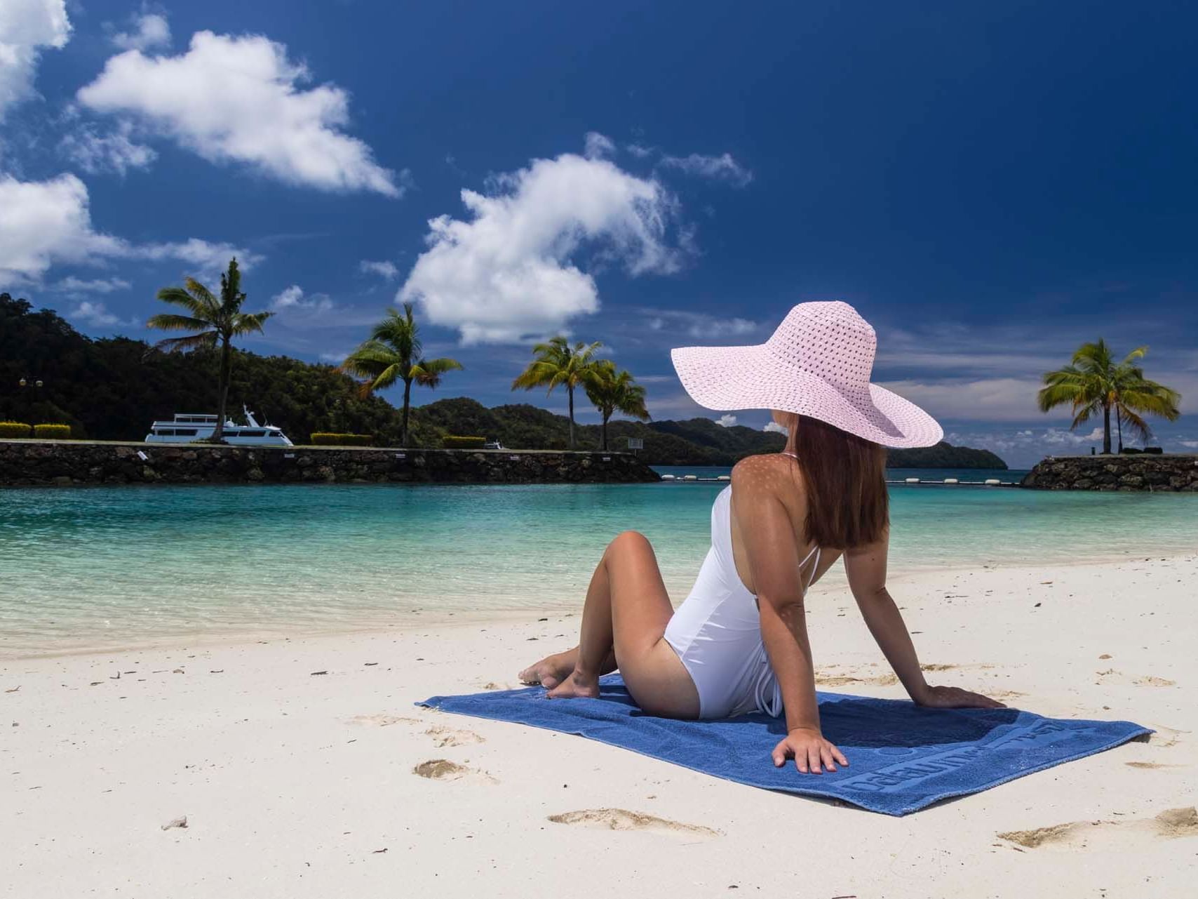 A girl sunbathing on a private beach at Palau Royal Resort