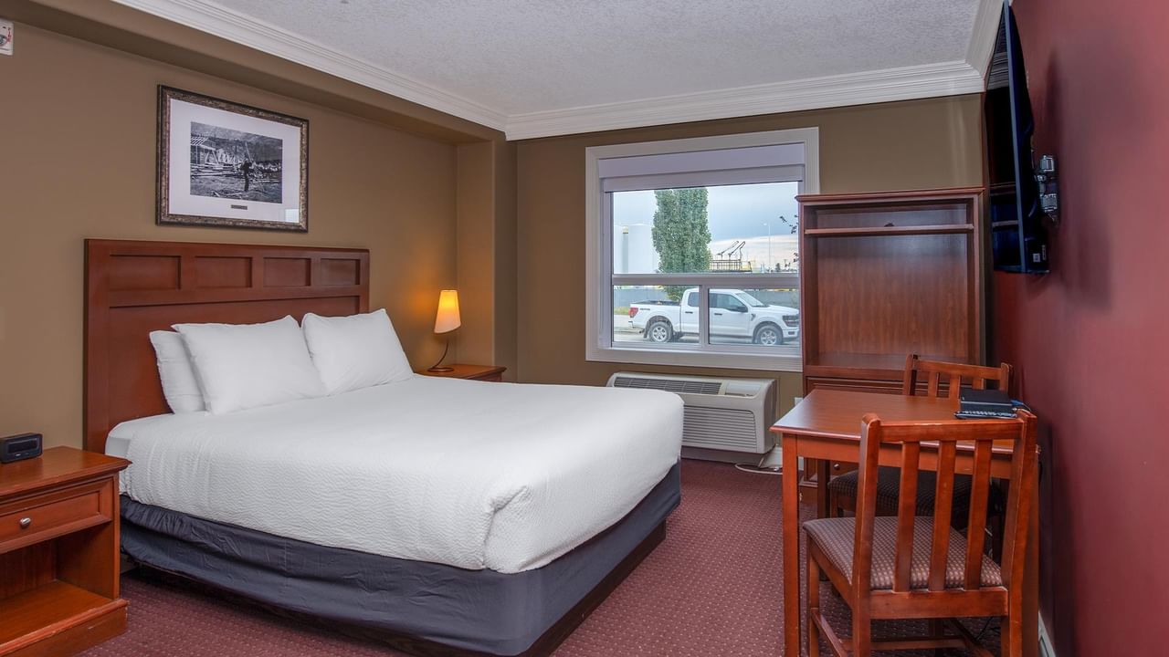 Guest room with wooden headboard, white bedding, work desk, and window view at Coast Edson Hotel.