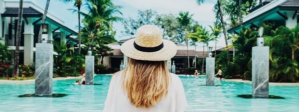 Woman in a hat and white shirt standing by the pool at Darwin Airport Hotels