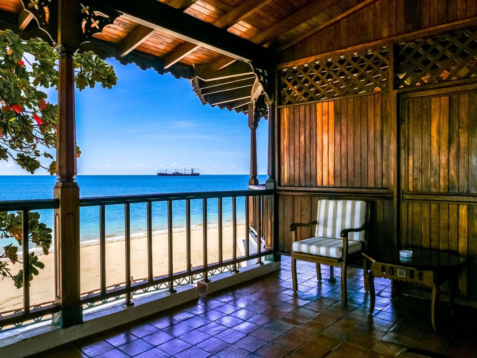 Armchair on a polished wooden balcony featuring panoramic views of the sandy beach and blue ocean at Zanzibar Serena Hotel
