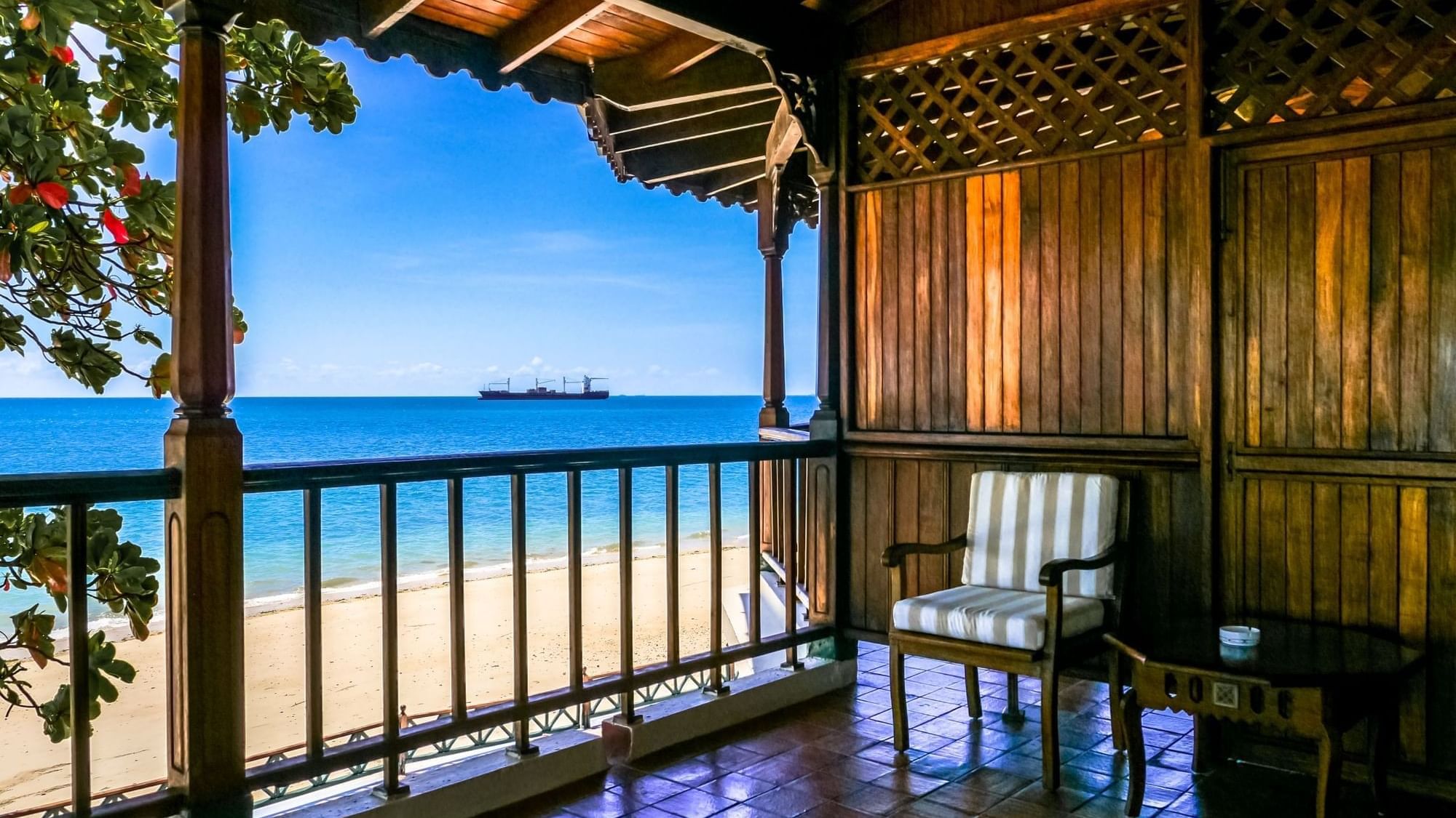 Armchair on a polished wooden balcony featuring panoramic views of the sandy beach and blue ocean at Zanzibar Serena Hotel