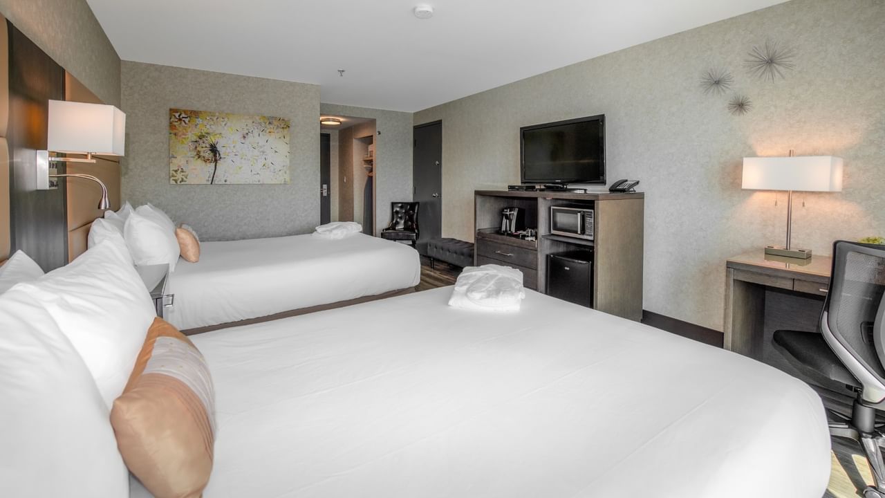 Coast Premium Two Queens with two queen beds, desk with chair, TV, and artwork at Coast Lonsdale Quay Hotel