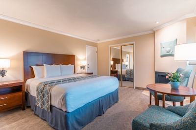 A warmly decorated guest room featuring a king bed, mirrored closet doors, and a small sitting area at Carmel Bay View Inn