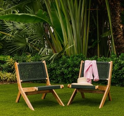 Two stylish wooden and woven mesh deck chairs on a green lawn at Kenmore Village Hotel, best hotels in South Beach Miami