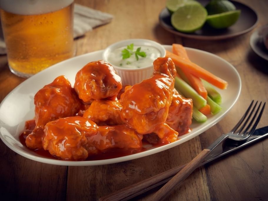 Hot Buffalo wing dish served with vegetables at One Hotels