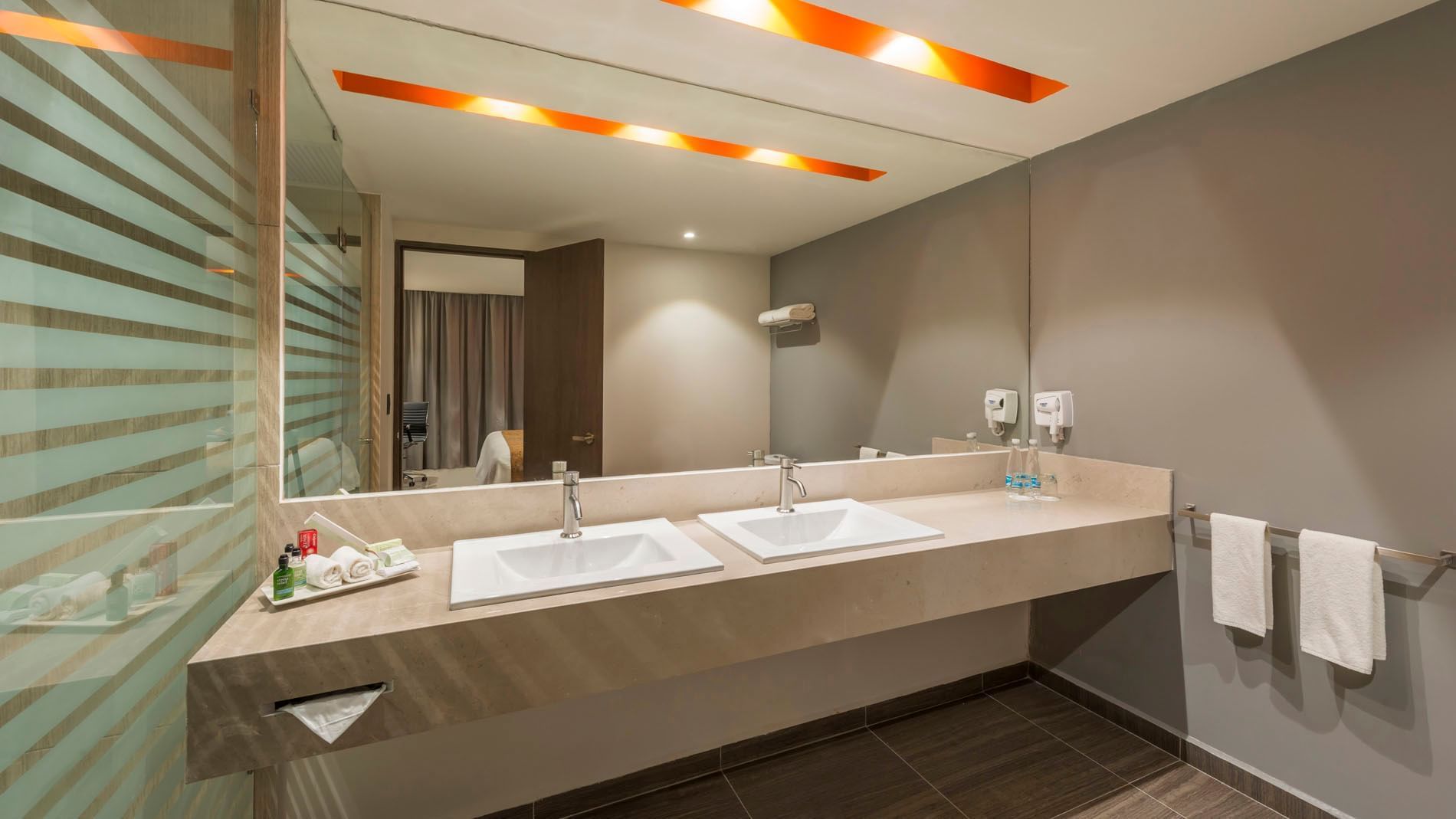 King Master Suite double vanity bathroom featuring a large mirror and warm recessed ceiling lights at Real Inn Celaya