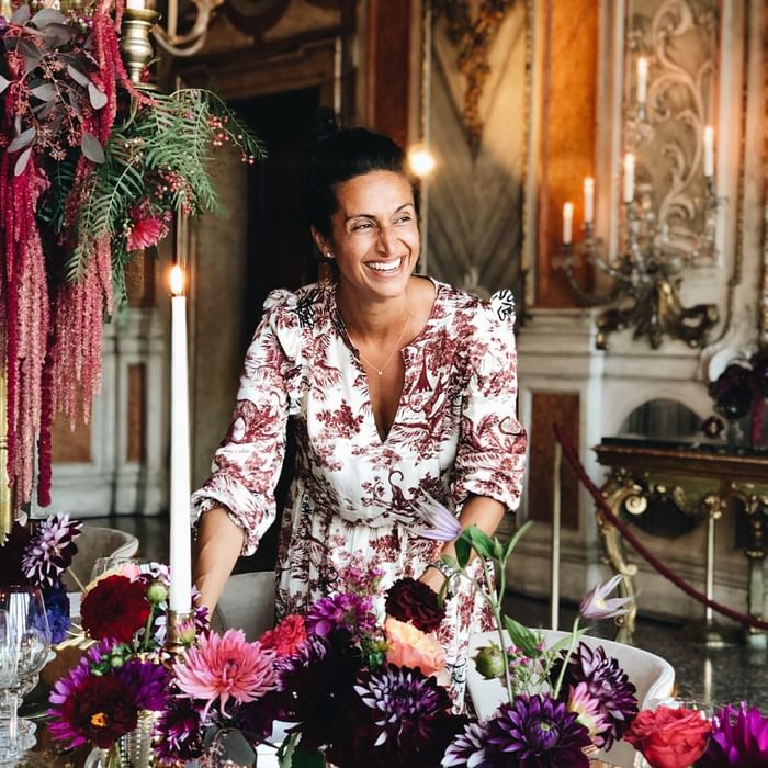 Woman arranging a flower-filled, candlelit table in an opulent room at Hotel Motto Vienna