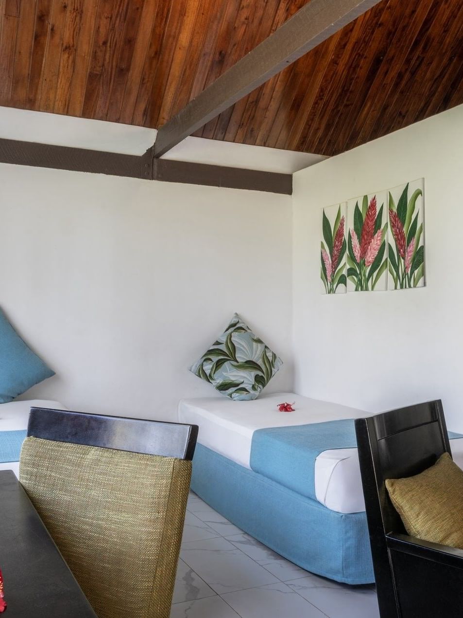 Twin beds with blue runners by a black armchair and desk in Garden View Villa at Tambua Sands Beach Resort