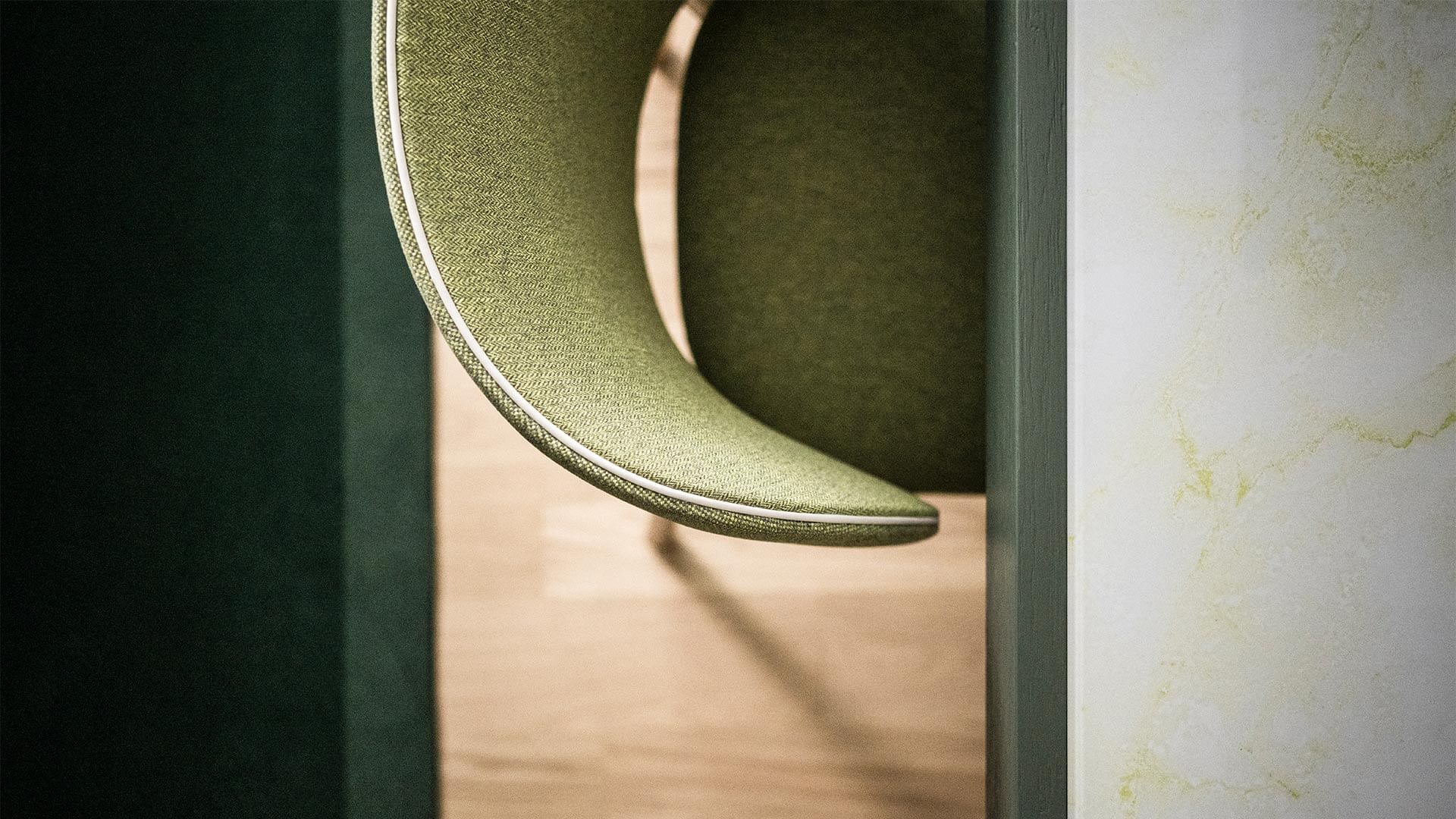 Grüner Stuhl mit heller Kante in Raumecke, umgeben von grüner und weißer Wand und Holzboden.