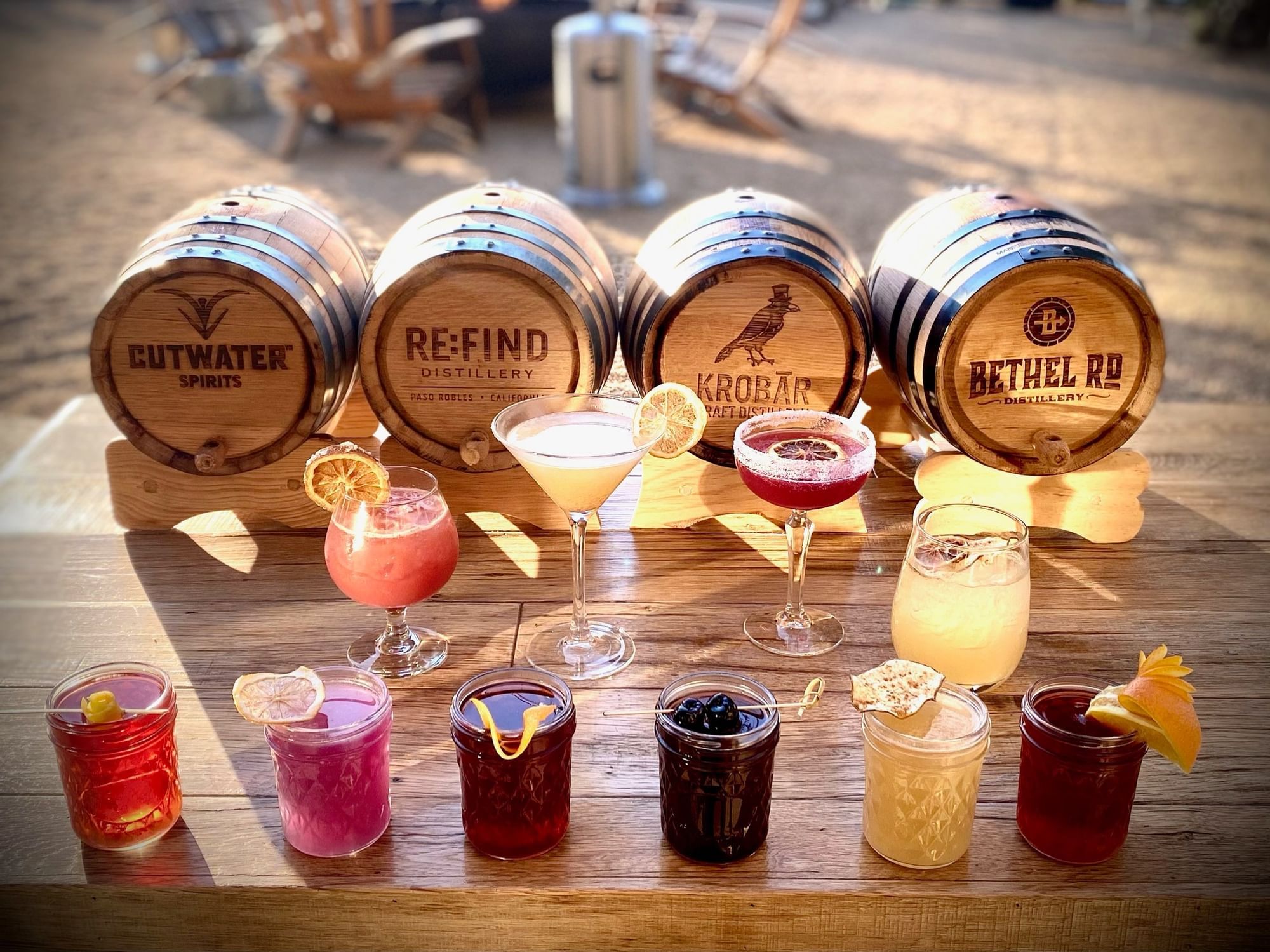 A line of handcrafted cocktails in front of barrels
