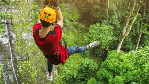 Guest on a zipline by a rocky cliff under Kula WILD Adventure Park near The Naviti Resort - Fiji