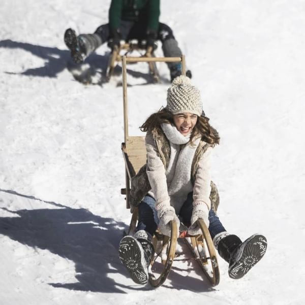 A girl enjoying a sleigh ride near Falkensteiner Hotels
