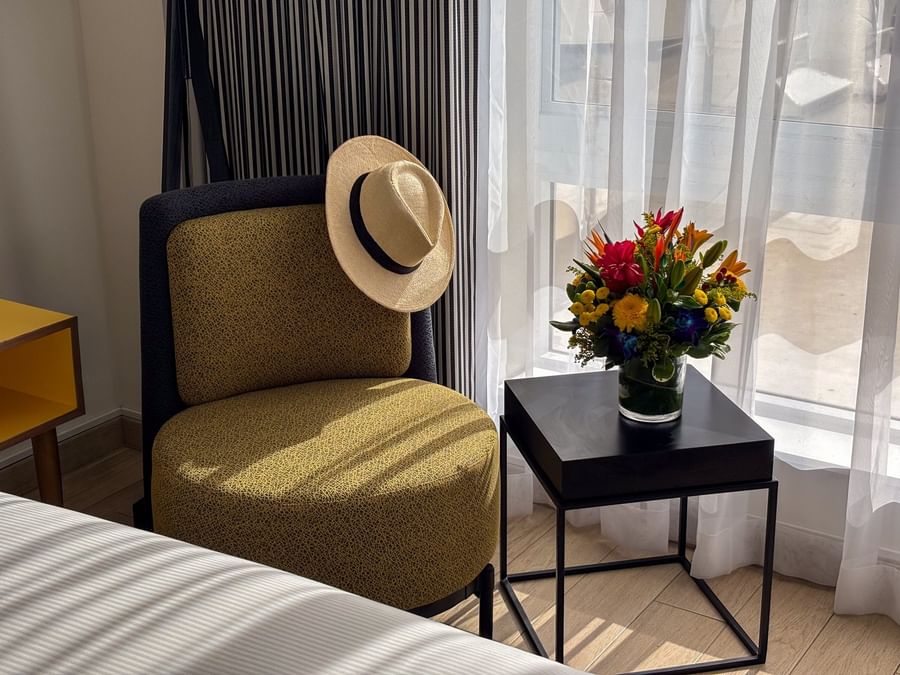 Yellow armchair with a straw hat by a vase of flowers on a black table in Island View at Warwick Paradise Island Bahamas
