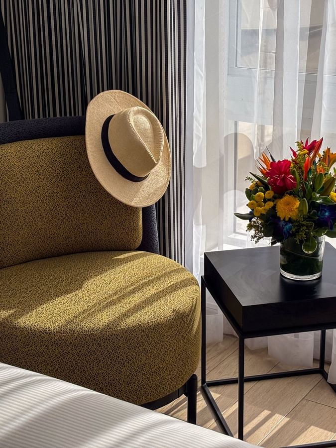 Yellow armchair with a straw hat by a vase on a black table in Island View Accessible at Warwick Paradise Island Bahamas