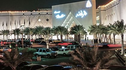 Al Rashid Mall by palm trees under a night sky, surrounding a busy parking area near Warwick Al Khobar