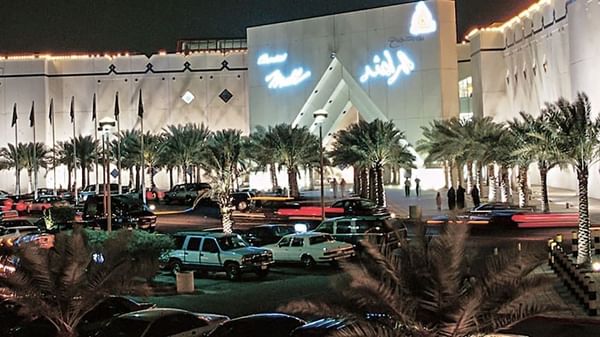 Al Rashid Mall by palm trees under a night sky, surrounding a busy parking area near Warwick Al Khobar