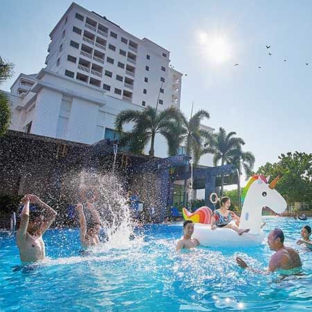 family taking a dip in the hotel pool together, with colourful pool inflatables - Lexis MY