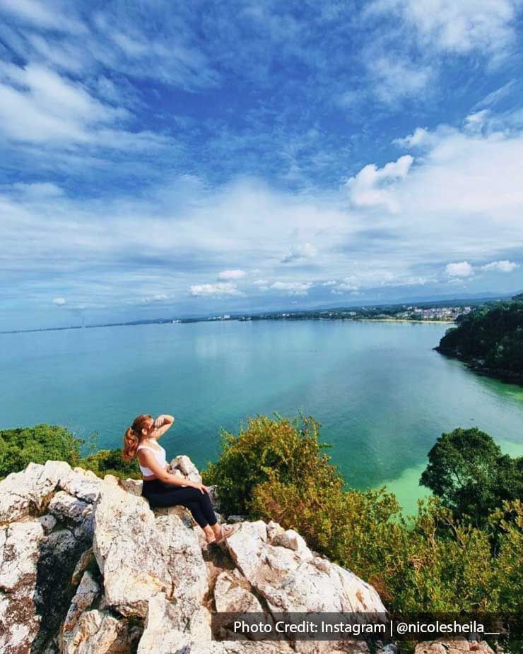 woman sitting on a rock while facing the ocean