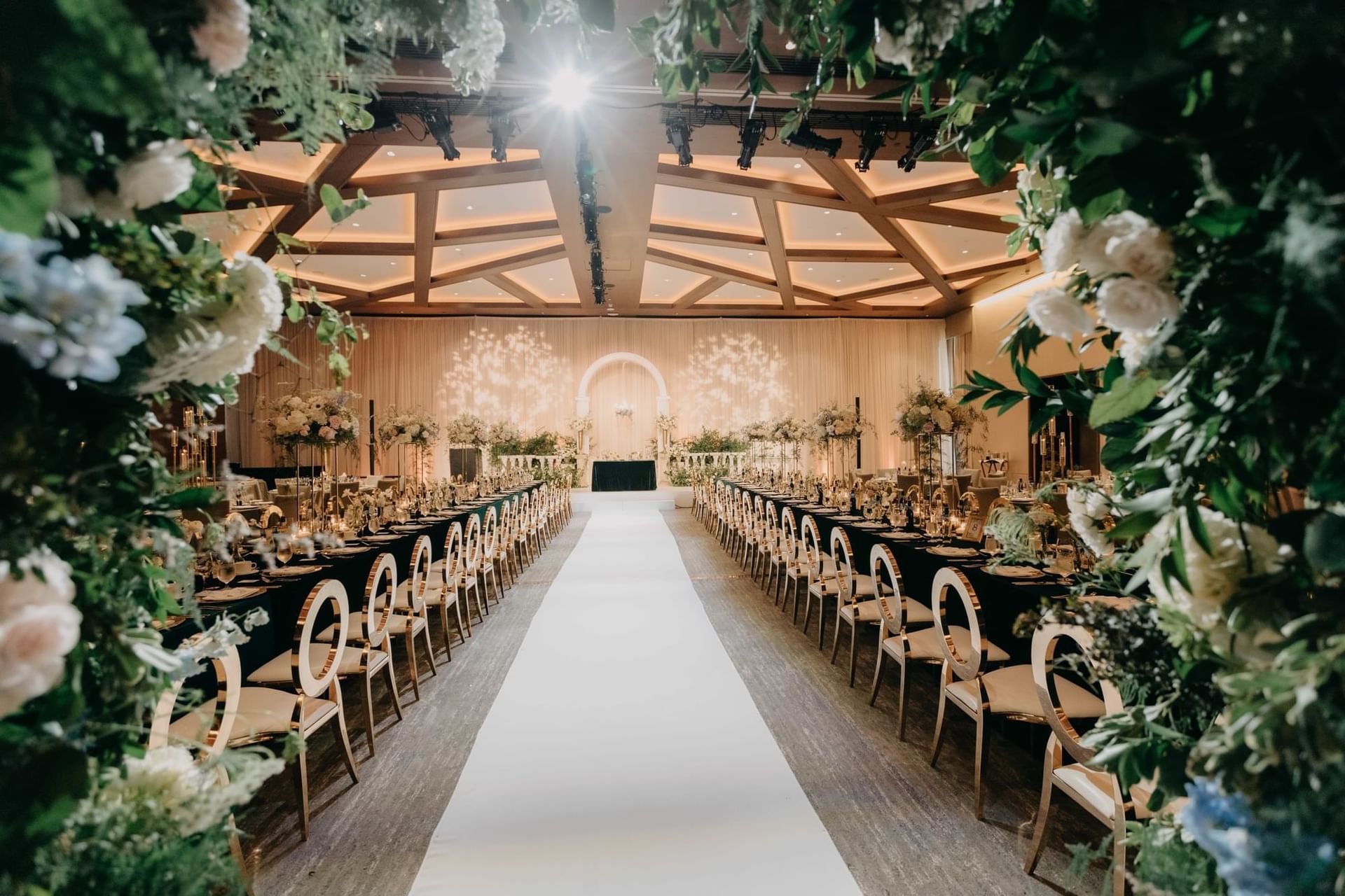 Decorated banquet hall at Paradox Vancouver with rows of tables, white runner, and floral arrangements on both sides.